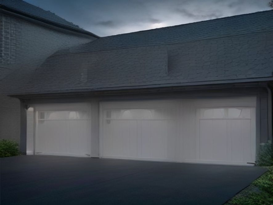 Traditional white paneled steel garage doors on a Long Island home at blue hour
